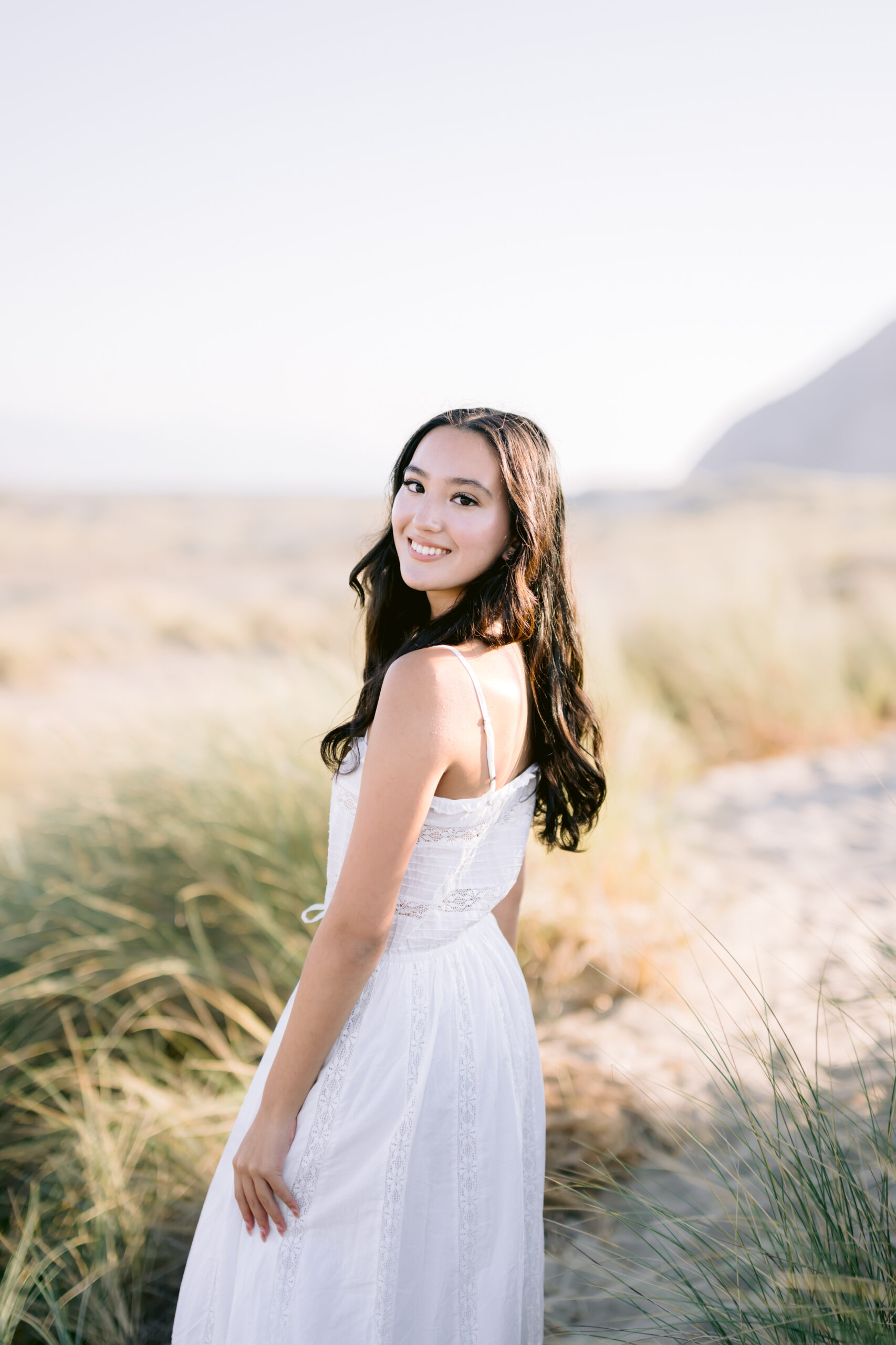 high school senior in white dress looking over her shoulder on a sandy path after a San Luis Obispo tutoring session